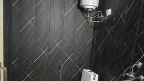 Un baño pequeño con inodoro blanco, calentador de agua instalado en la pared y cabezal de ducha.