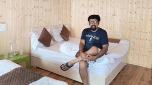 Una habitación con paneles de madera, una cama, un sofá y un ventilador de techo.