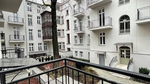 Un edificio residenziale a più piani con balconi, un albero in primo piano e un cortile in pietra.