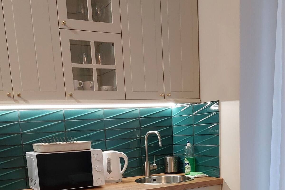 A kitchen with a microwave, kettle, and sink.