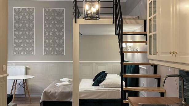 Una camera da letto moderna con un letto a castello, una scala in legno, un angolo cottura e un tavolo da pranzo.