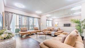 A modern living room with a sectional sofa, a round coffee table, and a large window with curtains.
