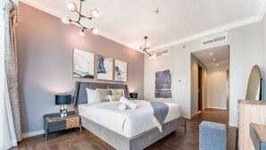 A modern bedroom with a large bed, bedside tables, a dresser, and artwork on the walls.