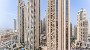 A high-rise residential building with multiple balconies, a rooftop pool, and a surrounding urban landscape.