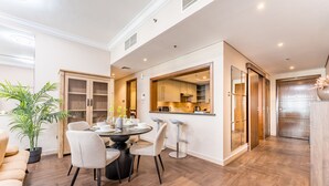A modern kitchen with wooden cabinets, a dining area with a round table and chairs, and a large mirror above the counter.