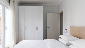 Un dormitorio con cama, armario y mesita de noche.
