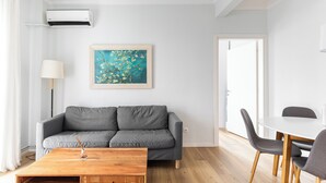 Una sala moderna con un sofá gris, una mesa de centro de madera y un cuadro en la pared.