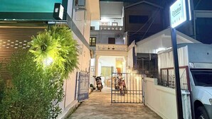 A narrow alleyway with a gated entrance leading to a building. There is a sign for 'Ocho de la Puerta' visible. - Ochatee Hostel (Chiang Mai)