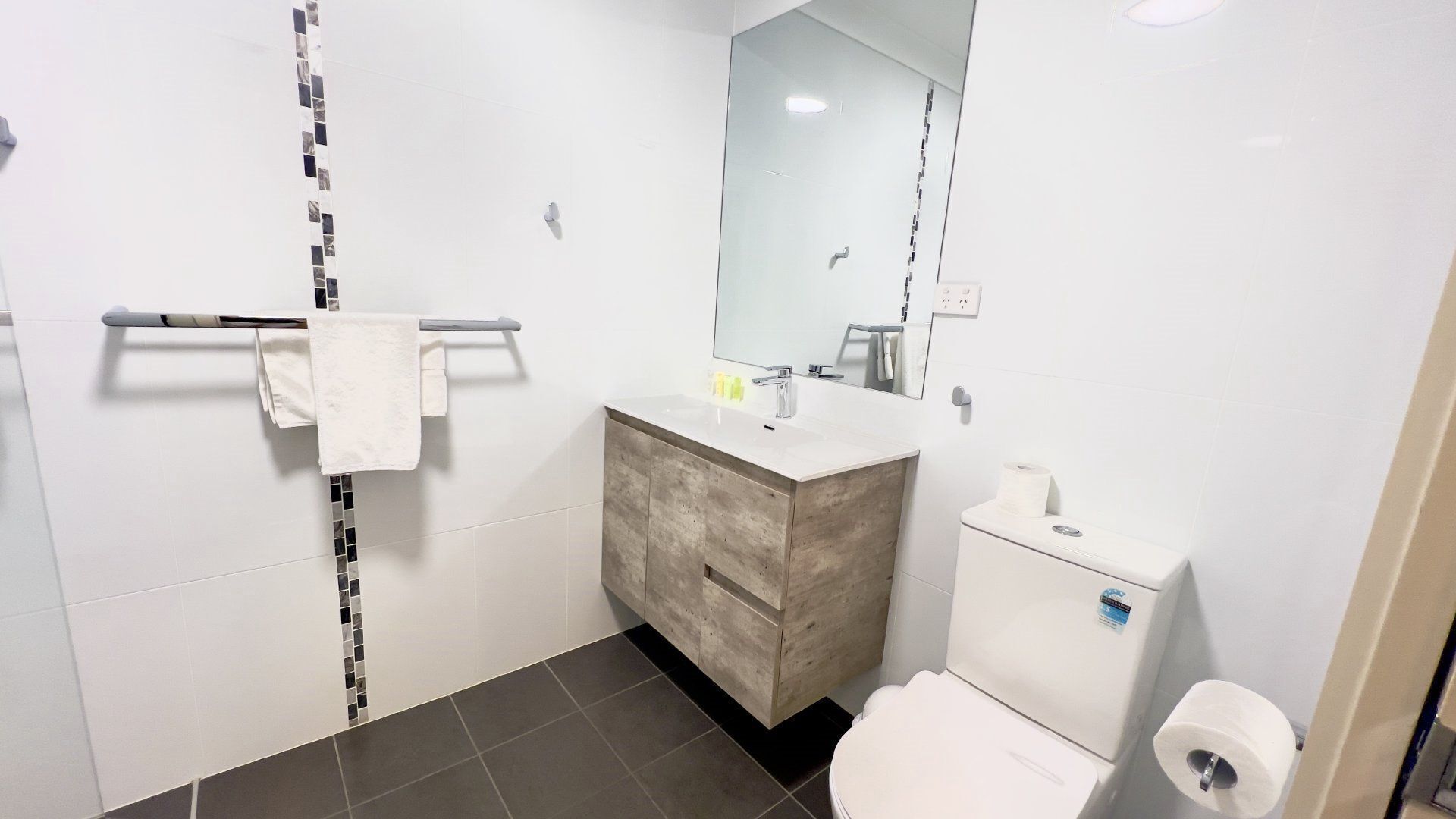 Une salle de bain moderne avec un lavabo blanc, un meuble-lavabo en bois et des toilettes.