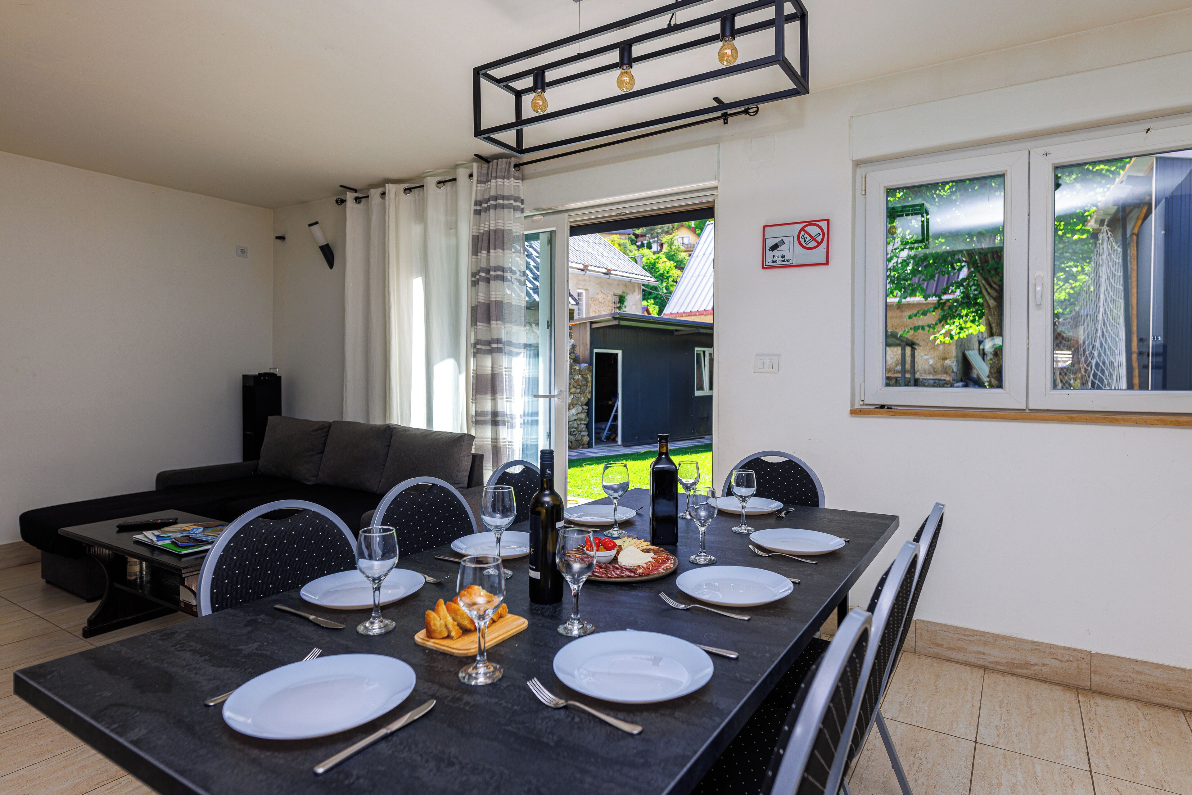 Un coin repas avec une table dressée pour six personnes, un canapé et une vue sur le jardin.