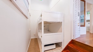 A bunk bed in a room with white walls and a wooden floor.