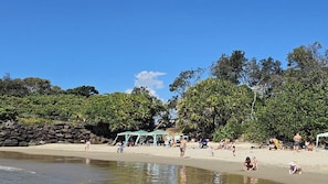 Una platja amb gent, una tenda i arbres.