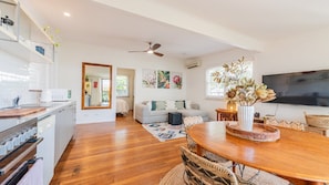 A spacious living area with a wooden dining table, a sofa, and a television.