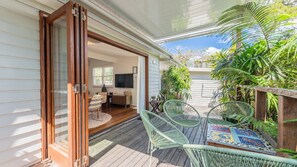 A covered patio with a wooden deck, outdoor seating, and a view of the garden. - Welcome to Casablanca, a stylish cottage perfectly positioned in the Heart of Bruns (BRUNSWICK HEADS)