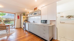 A modern kitchen with white cabinets, a microwave, and a dining area with a table and chairs.