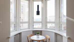 A bay window with a round table and chairs, a hanging pendant light, and a potted plant. - Hotel-standard design apartment with sea view (Helsinki)