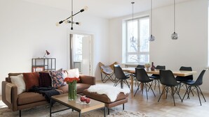 A modern living room with a sofa, coffee table, and dining area with chairs and a table. - Hotel-standard design apartment with sea view (Helsinki)