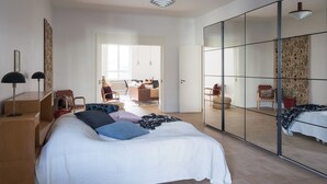 A modern bedroom with a large bed, a wardrobe with a mirror, and a desk with a chair. - Hotel-standard design apartment with sea view (Helsinki)