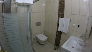 Ein Badezimmer mit Duschkabine, Toilette, Waschbecken und Handtuchhalter.