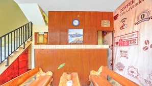 Un mostrador de recepción de madera con un reloj, un cartel de una montaña y una pared con logotipos de cafeterías.