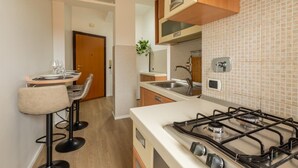 Une cuisine compacte équipée d’une cuisinière à gaz, d’un évier et d’un coin repas avec une table et des chaises.