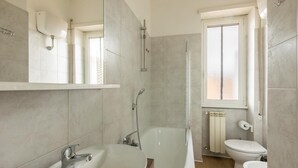 Une salle de bain moderne équipée d’une baignoire, d’un lavabo, de toilettes et d’une douche.
