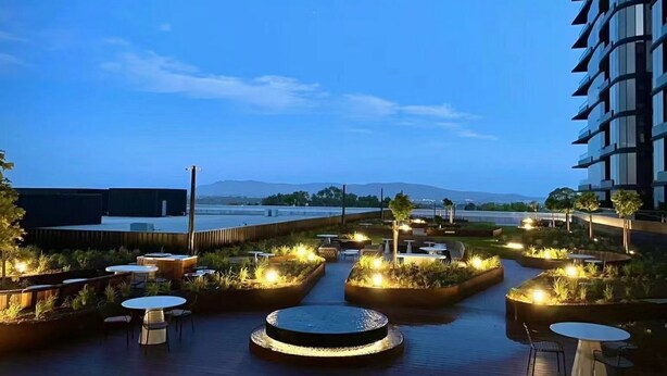 Terraza en la azotea con mobiliario exterior y fuente de agua, con vistas a un paisaje urbano y montañas lejanas.