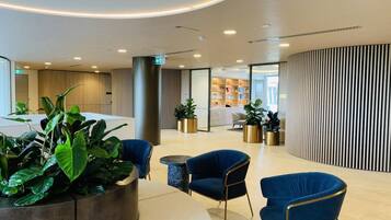 A modern lobby with seating areas, a reception desk, and a plant arrangement.