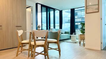 A modern living room with a dining area, large windows, and a view of the outdoors.