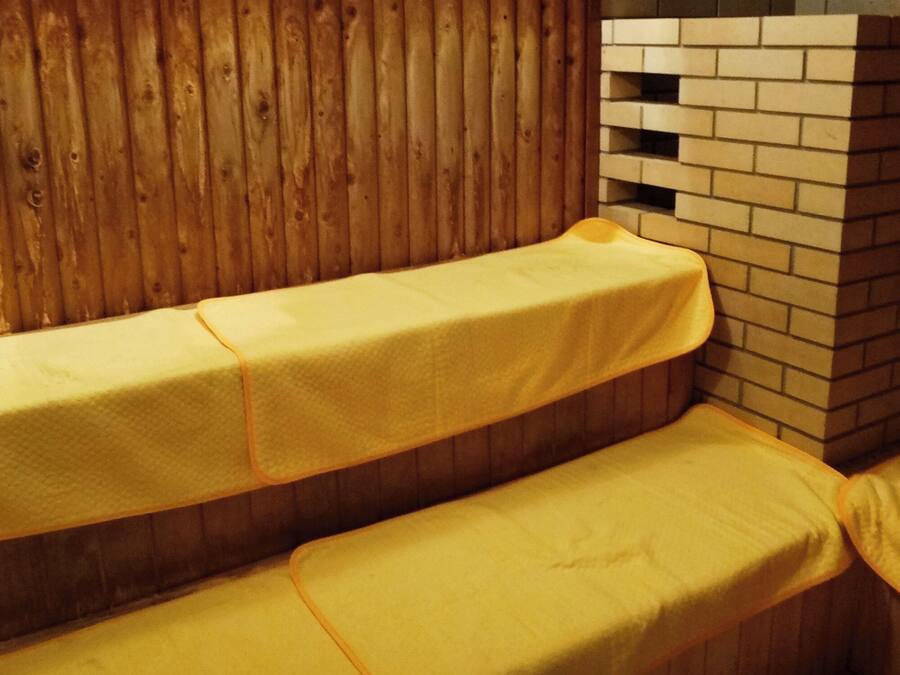 Eine Holzwand mit Ziegeloptik und zwei gelb gepolsterten Bänken.