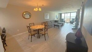 A spacious living area with a round dining table, a sofa, and a view to the outside. - Island End Paradise - 2 Bedroom Beachfront (Fort Myers Beach)