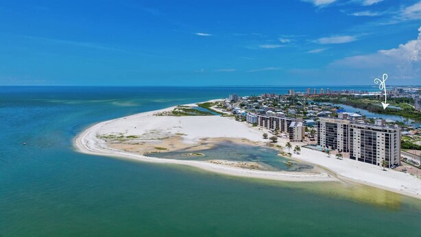 An aerial view of a coastal resort with beachfront properties, clear blue waters, and a clear sky. - Island End Paradise - 2 Bedroom Beachfront (Fort Myers Beach)