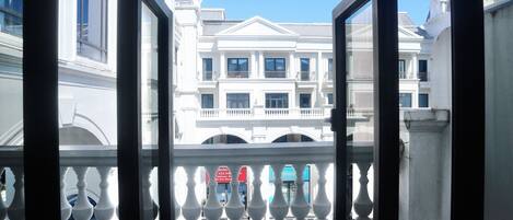 A view from a balcony with a balustrade, overlooking a row of white buildings with multiple stories and balconies.