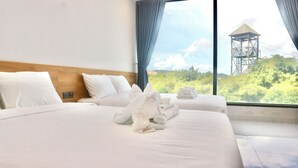 A hotel room with two beds, a wooden headboard, and a large window with a view of a tower and greenery. - Blue Waves Hotel (Phu Quoc)