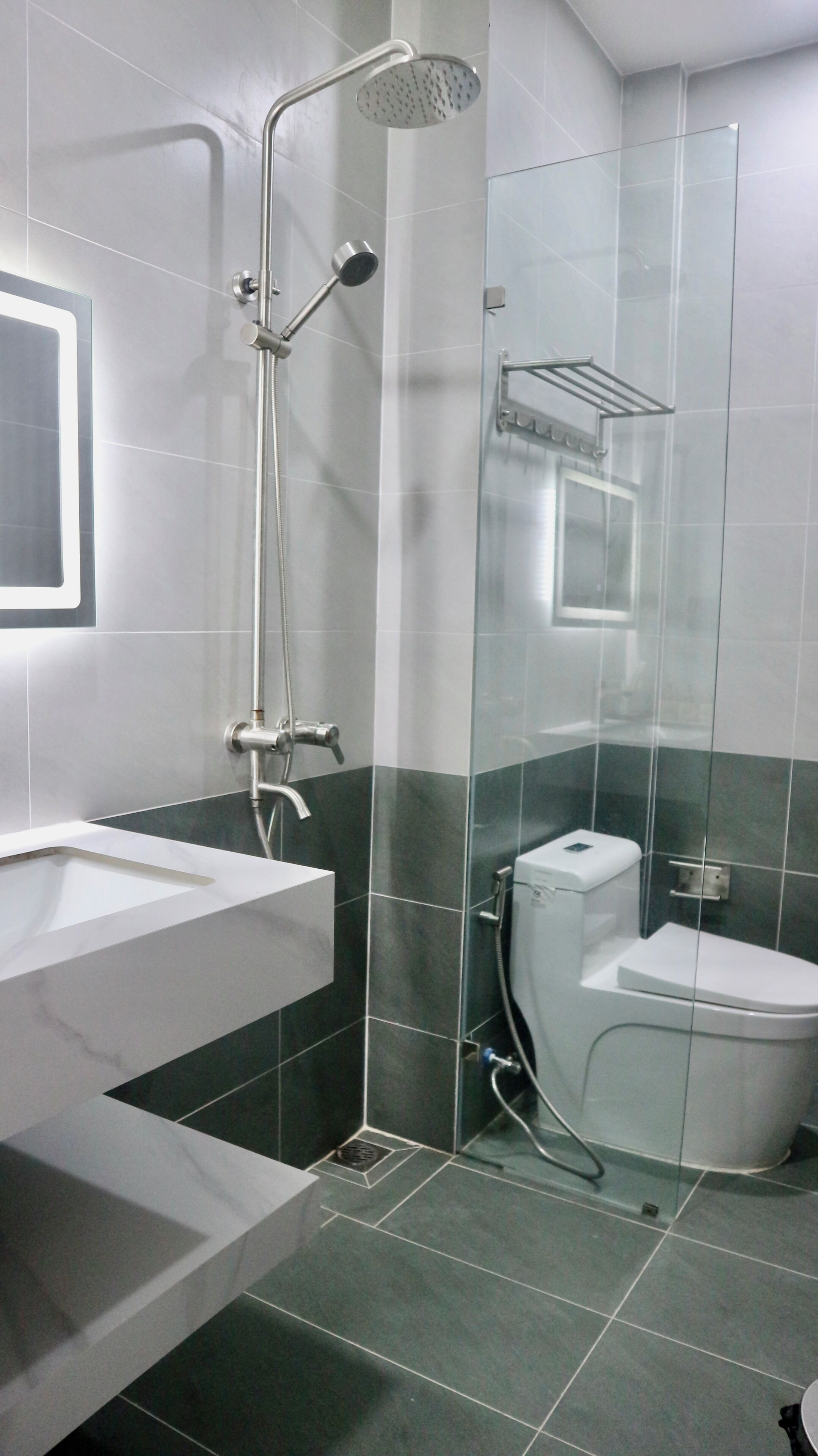 A modern bathroom with a glass-enclosed shower, a white sink, and a toilet.