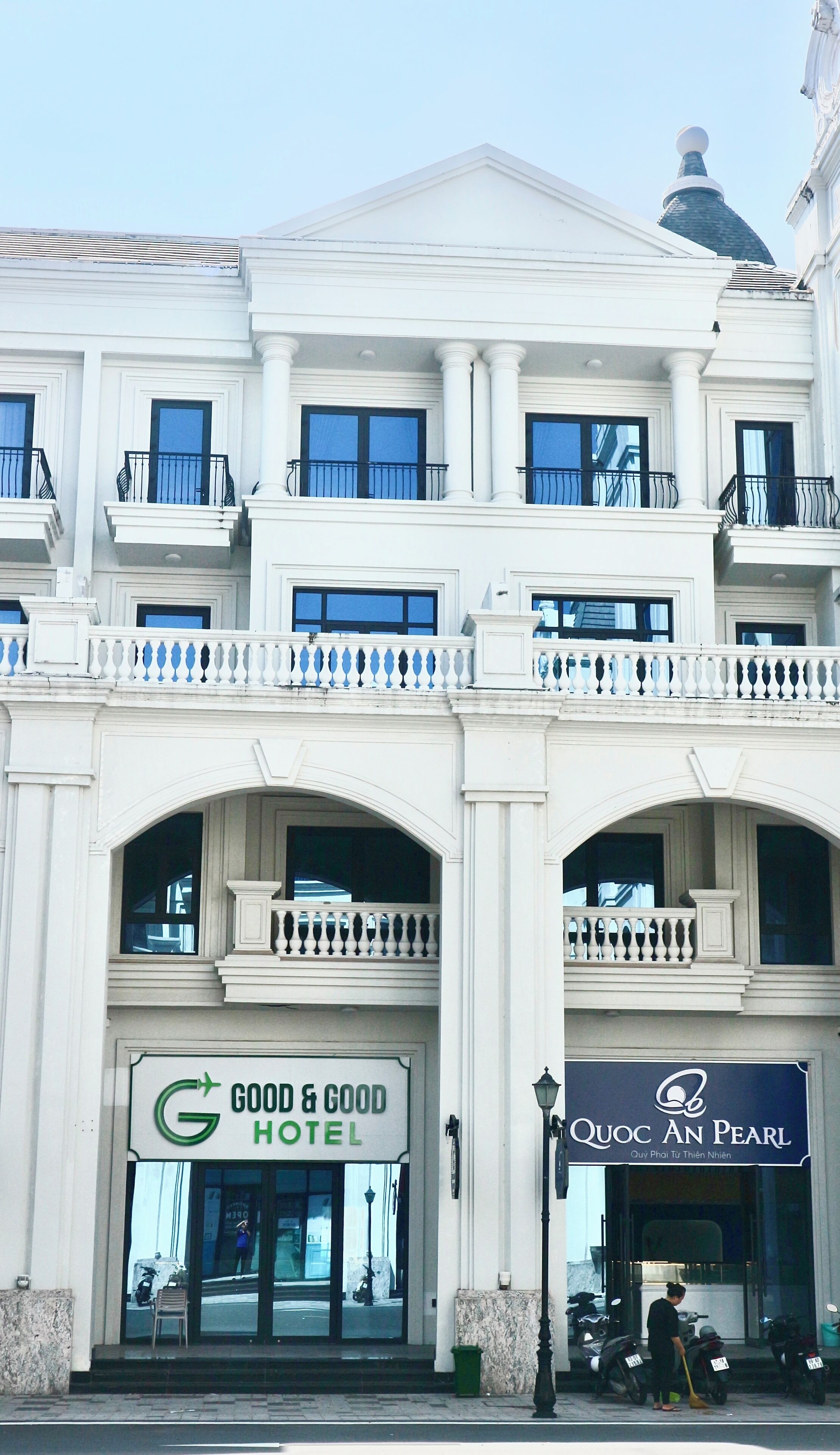 En bygning med et skilt, der viser 'Good & Good Hotel', og et andet skilt for 'Quoc An Pearl'.