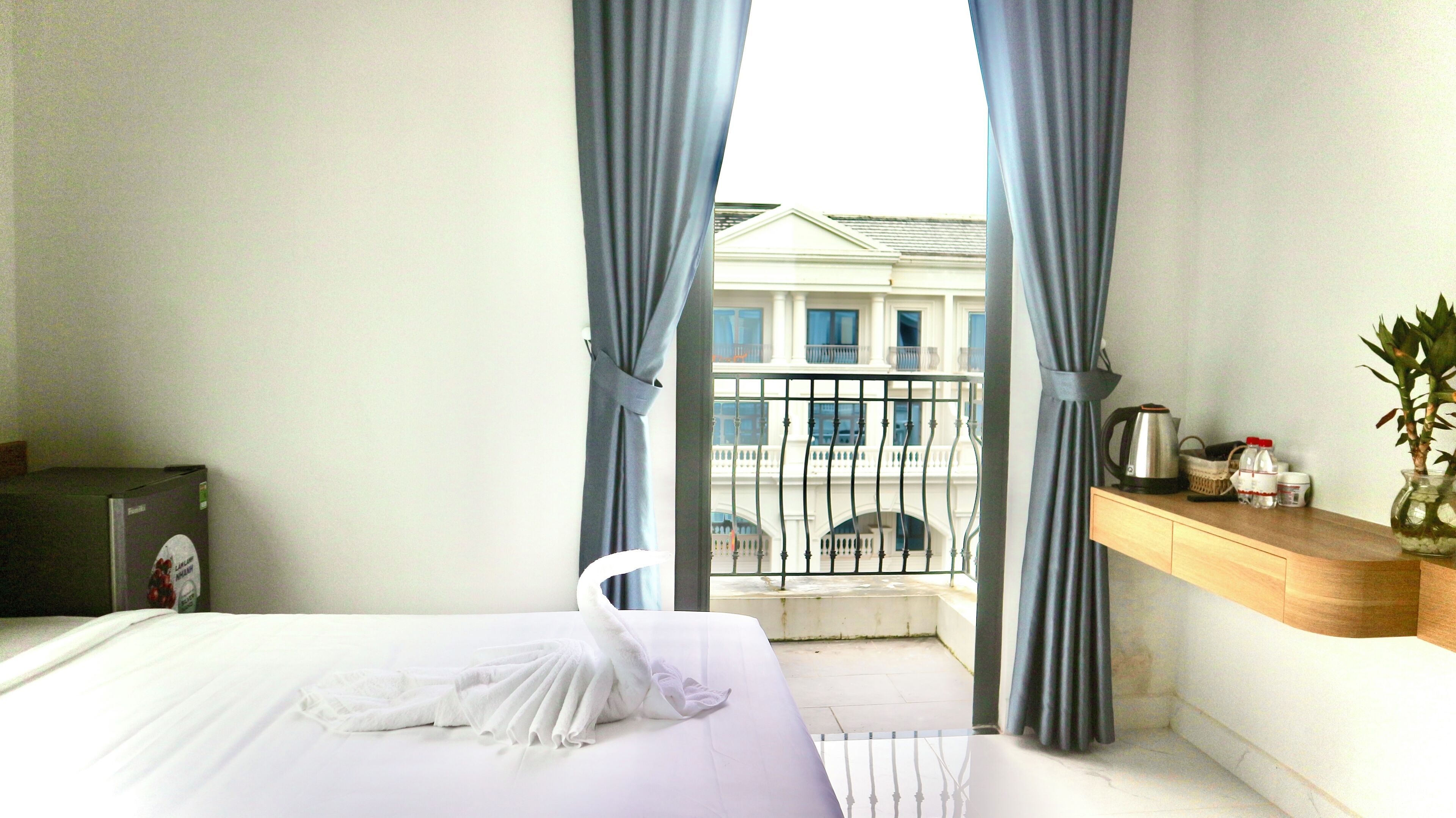 Habitación de hotel con cama, escritorio, silla y balcón con vista a un edificio.