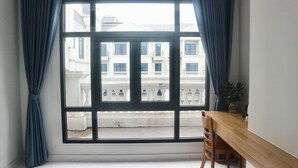 A room with a large window, a wooden desk, and a chair. - Blue Waves Hotel (Phu Quoc)