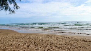 A sandy beach with waves, a clear sky, and a distant boat. - Blue Waves Hotel (Phu Quoc)