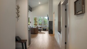 A modern interior with a long hallway leading to a living area with a sofa and a TV.
