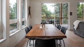 A spacious dining area with a wooden table and chairs, large windows offering a view of the outdoors, and a balcony with outdoor seating.