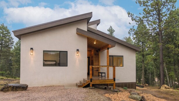 A modern two-story house with a wooden deck and a stone pathway leading to the entrance.