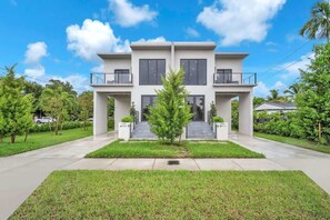 A modern two-story house with a central staircase, surrounded by well-maintained lawns and trees. - Casa Bella l Sleeps 10 l Near Freedom Park & MIA (Miami)