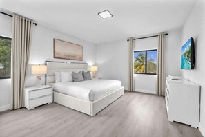 A modern bedroom with a large bed, bedside tables, a TV, and a window with curtains. - Casa Bella l Sleeps 10 l Near Freedom Park & MIA (Miami)