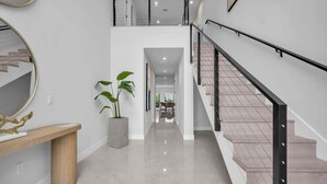 Un intérieur moderne avec un escalier, une plante en pot et un banc en bois.