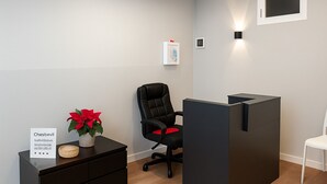 Espaço de escritório moderno com uma poltrona de couro preta, uma escrivaninha com planta em vaso e um divisória escura.