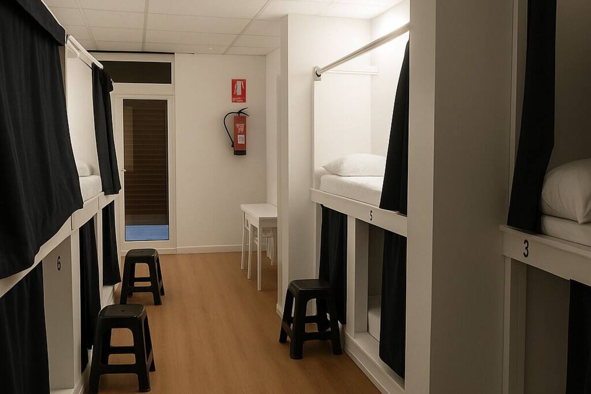A dormitory room with bunk beds, a small table, and a fire extinguisher.