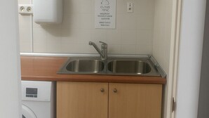 Uma cozinha pequena com armários de madeira, uma pia de aço inoxidável e uma máquina de lavar.
