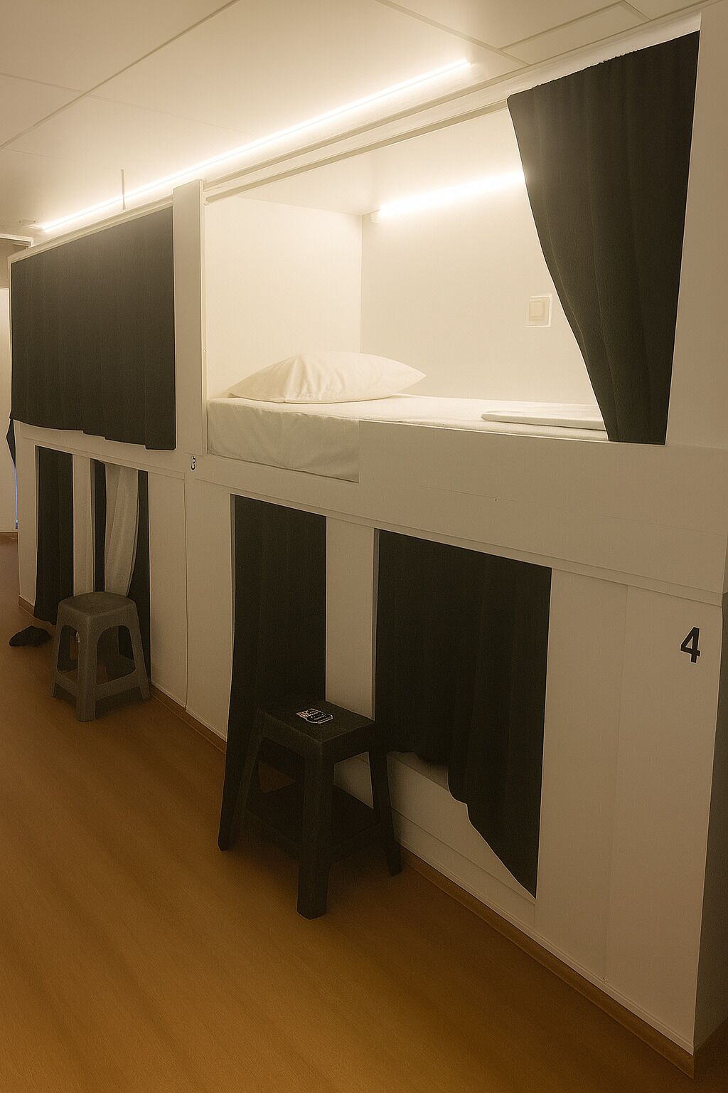 A dormitory room with bunk beds, a small stool, and a number '4' on the wall.