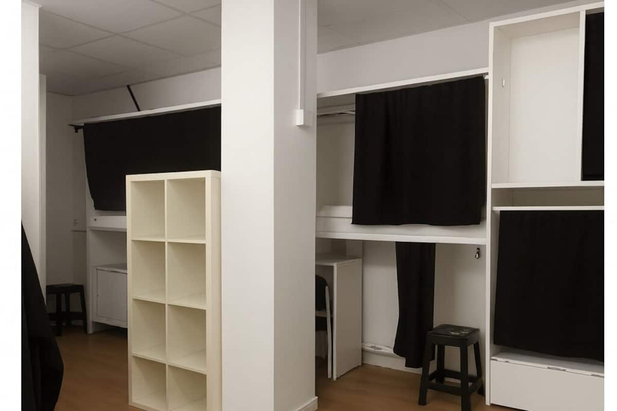 A room with a bunk bed, a white wardrobe, a small stool, and a white cabinet.